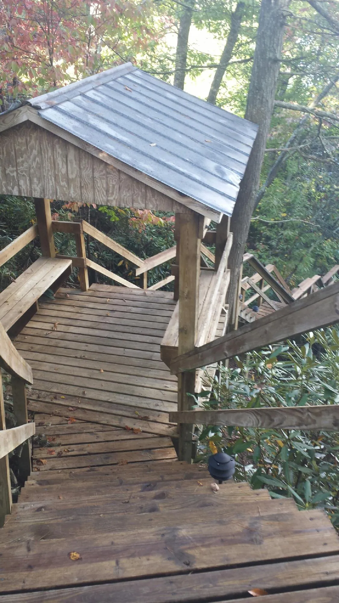 Metal roofed shelter over wooden steps on a wooded walkway — Skylight Repair & Installation work by our crew in Glenmont