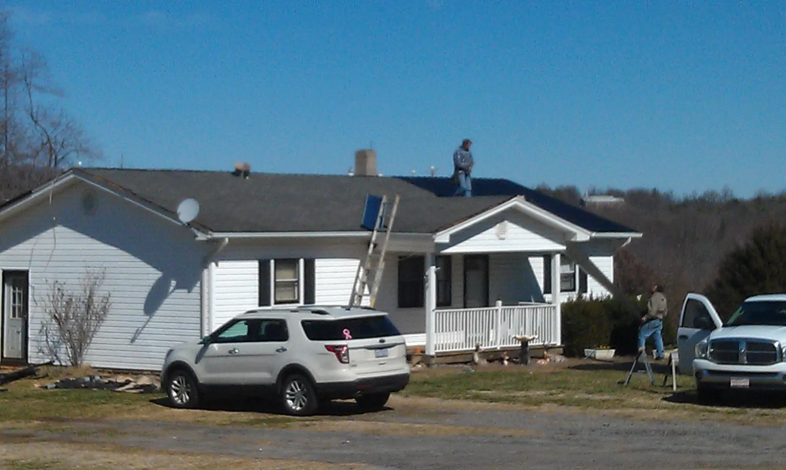 Roofers stripping shingles from a white ranch house roof in Glenmont
